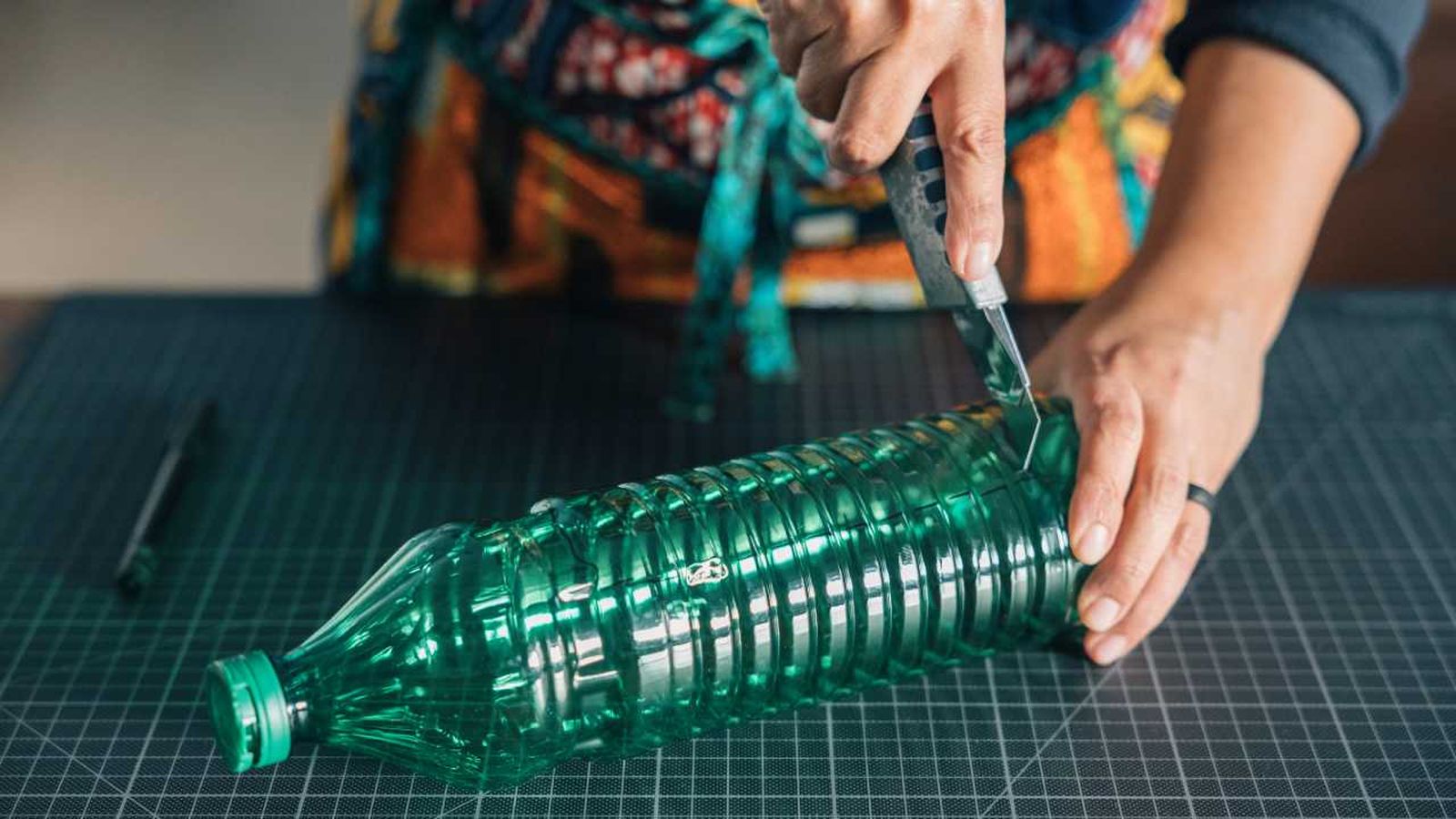 Mujer cortando una botella de plástico.