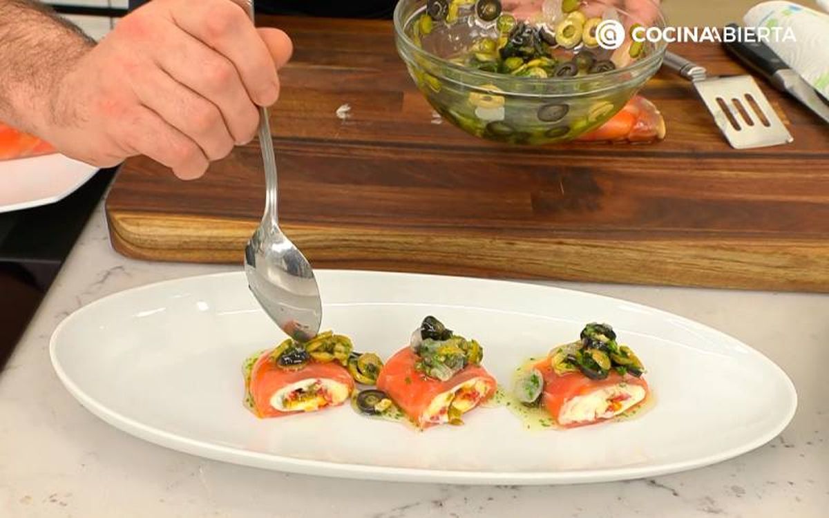 Elaboración de la receta de rulo de salmón ahumado relleno de brandada - Sirve los rulos de salmón cortados y aliñados