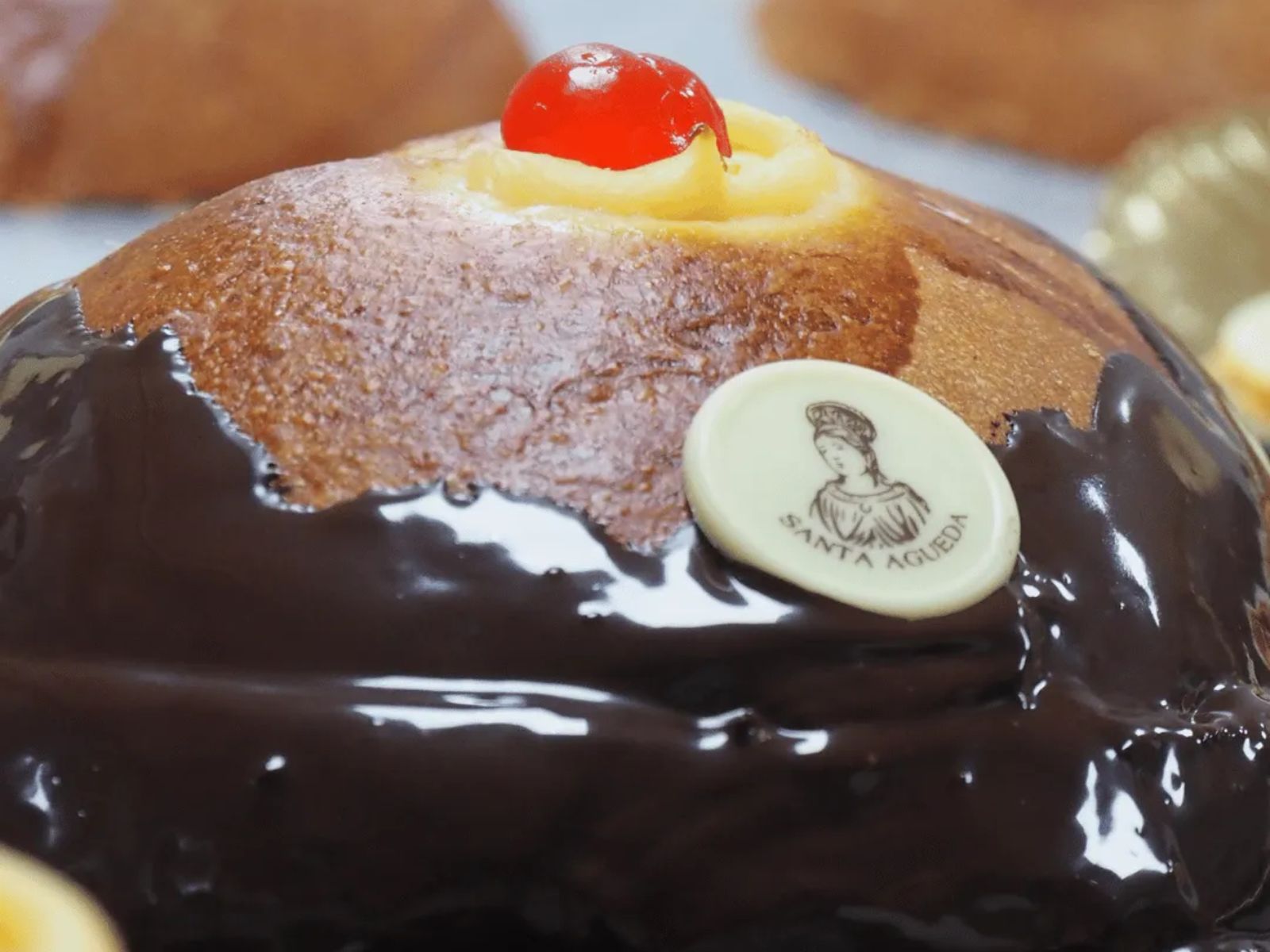 Bollo relleno y cubierto de chocolate, rematado con guinda, en una de las versiones tradicionales de la tetica de Santa Águeda.