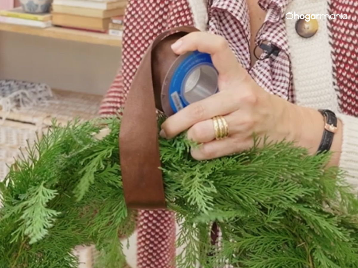 Fija la cinta que servirá para colgar la corona, asegurándola en la parte superior con unas grapas.