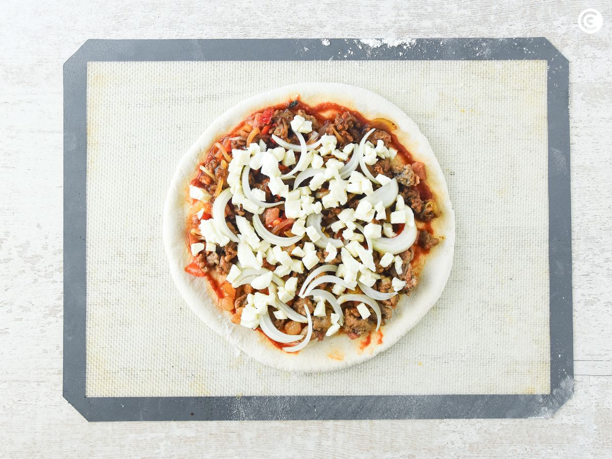Coloca todos los ingredientes sobre la masa de pizza
