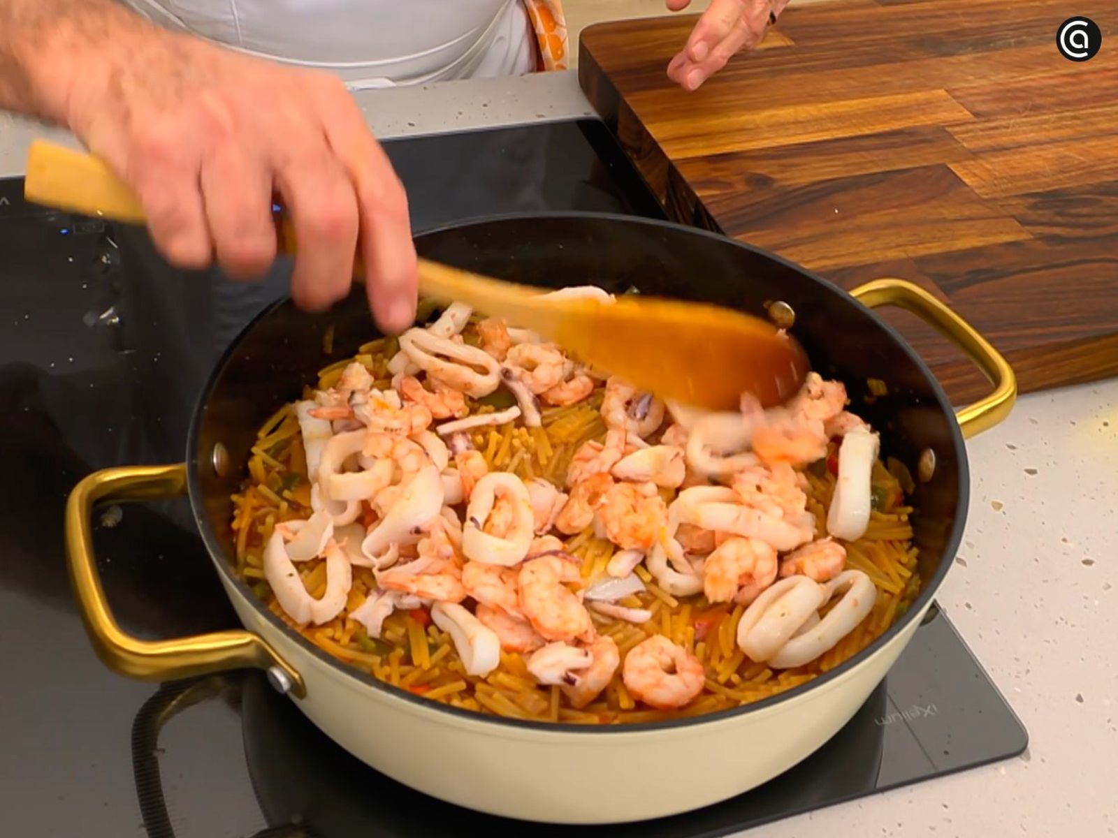 Agrega a la tartera las gambas y los calamares para que se integren