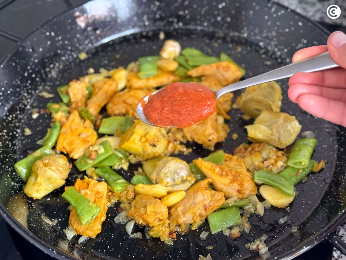 Agregar una cucharada de tomate a la paella vegana