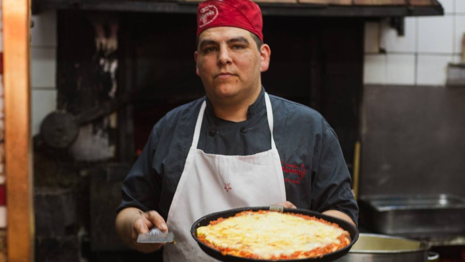 Pizzero en la tradicional pizzería Güerrín de Buenos Aires, preparando una pizza al molde.