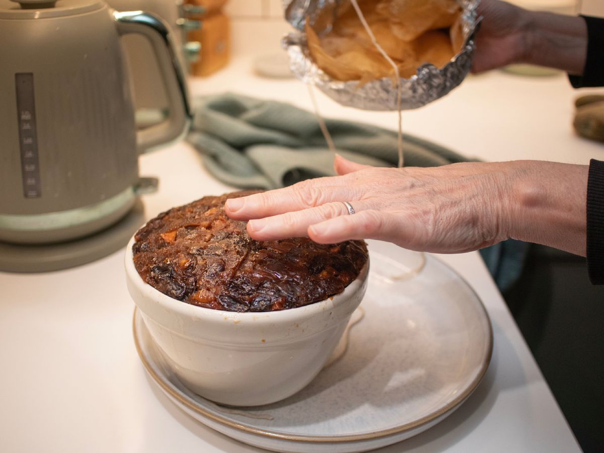 Al retirar el papel y abrir el molde aparece el pudin ya cocido, oscuro, brillante y lleno de fruta.