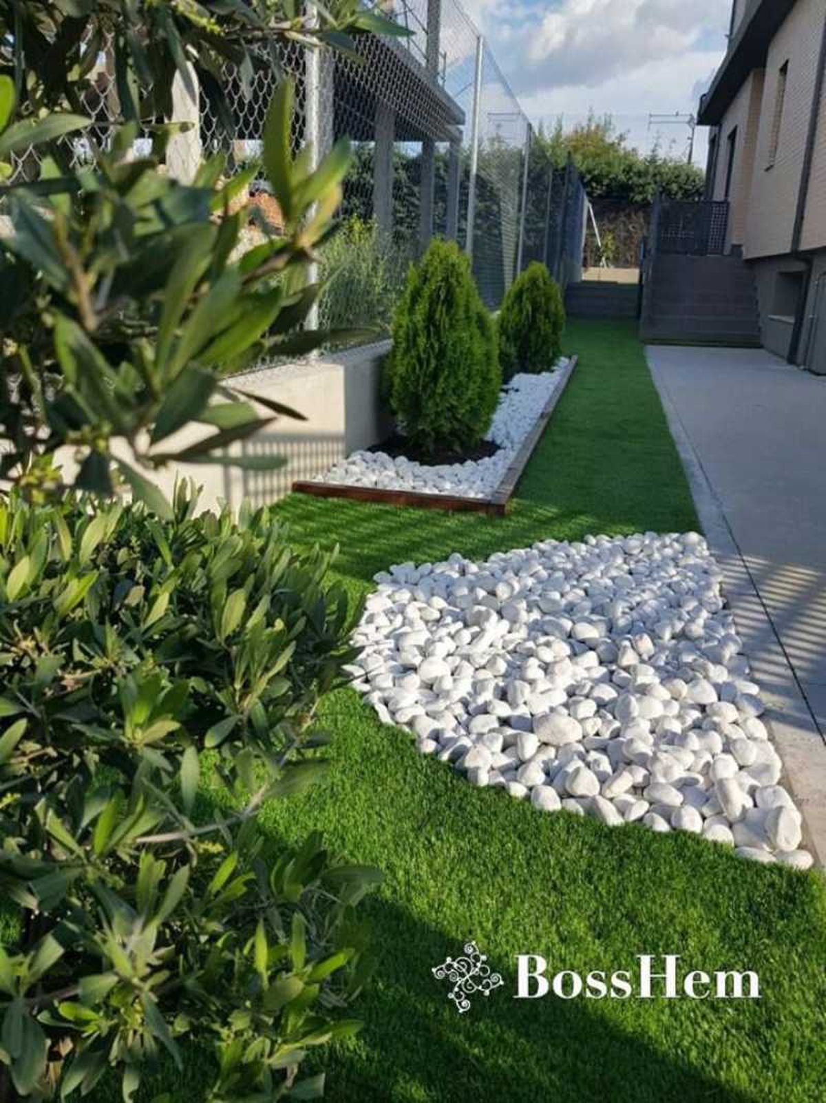 Jardín pequeño con césped artificial y piedras.