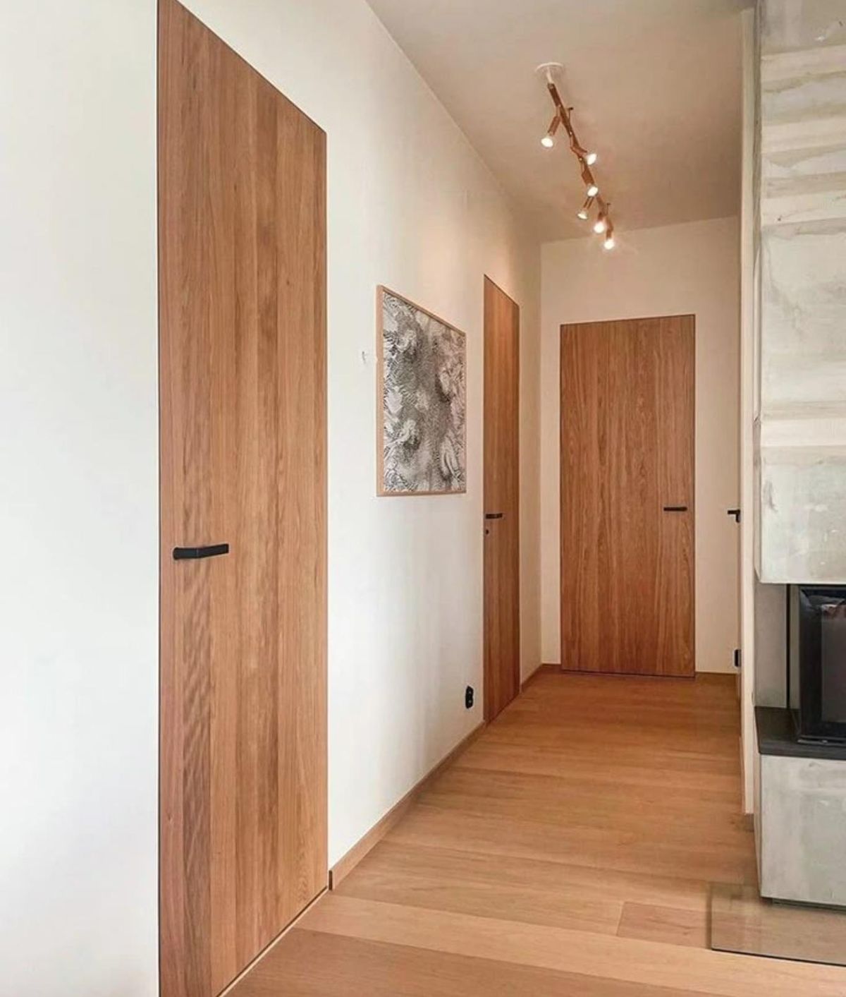 Rincón de casa con puertas y suelo de madera en tonos similares.