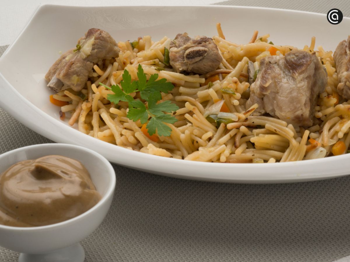 Fideos con costilla ibérica acompañados de mahonesa de ajo negro, un toque innovador en la cocina tradicional.