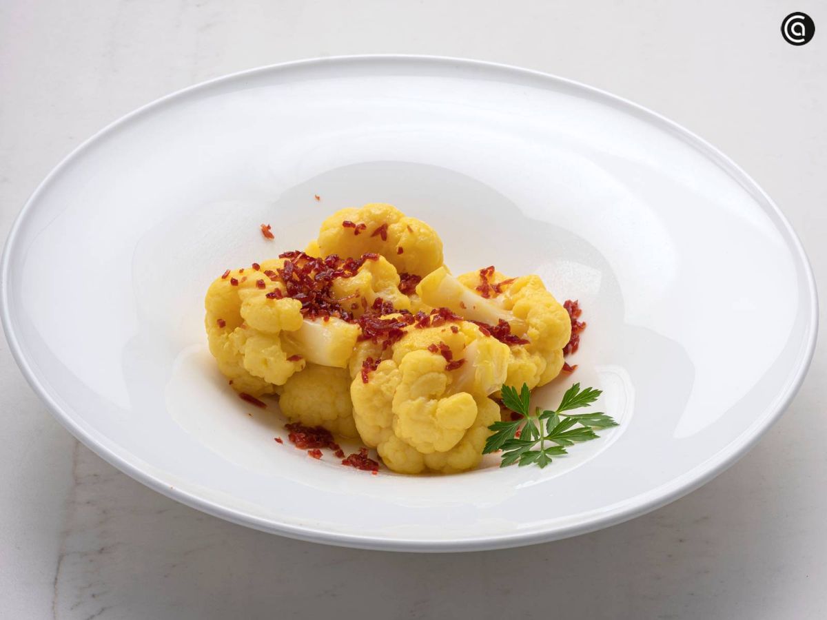 Emplata la coliflor y añade aceite, el jamón molido y unas hojas de perejil