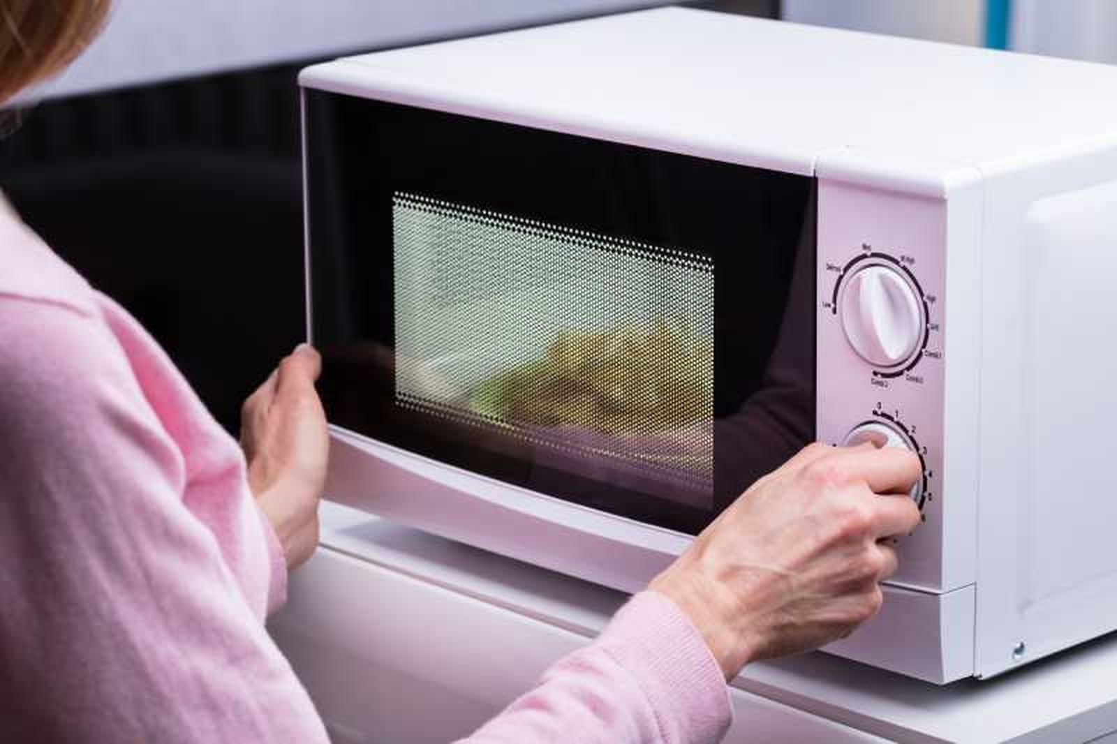 Mujer poniendo el microondas.