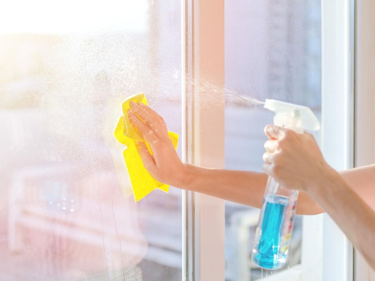 Manos de mujer limpiando los cristales.