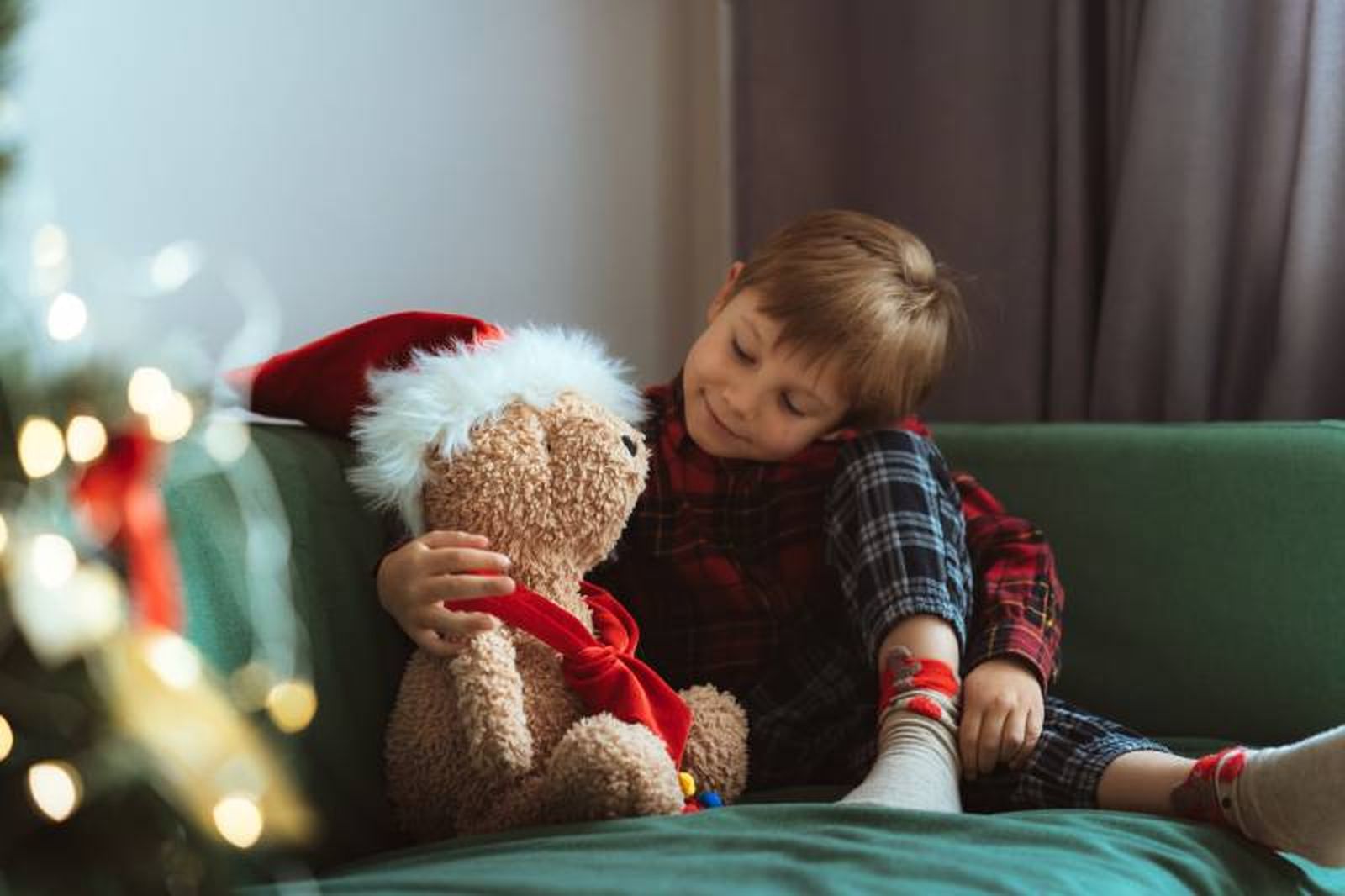 Niño en un sofá con un osito navideño. Niño en un sofá con un osito navideño.