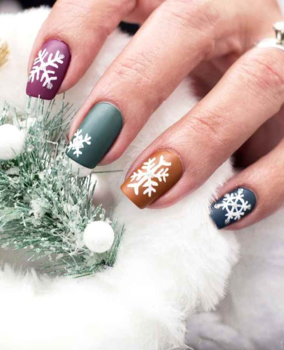 Uñas de Navidad de colores con copos de nieve en blanco