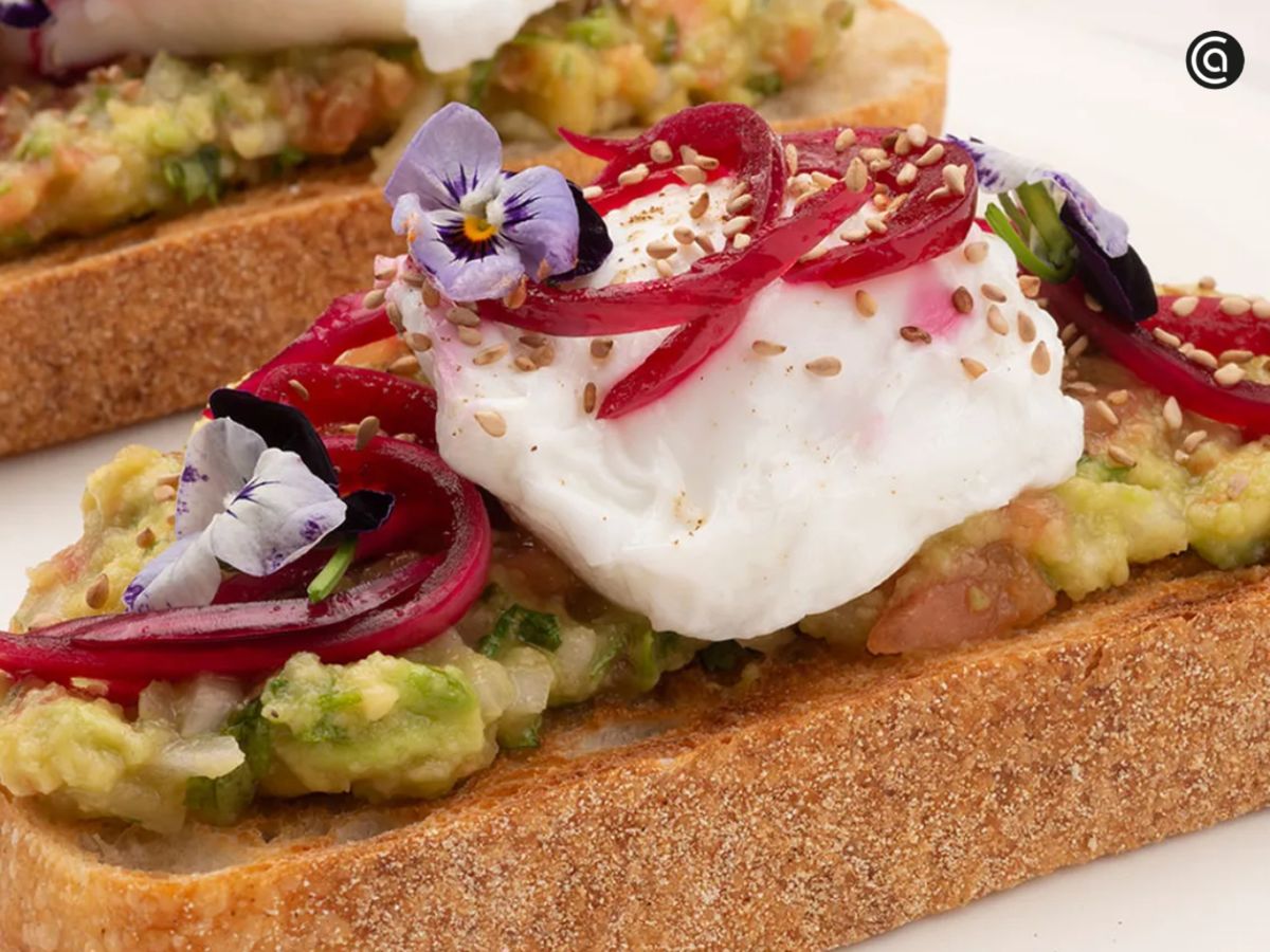 Una tosta de guacamole con huevo escalfado y flores comestibles, tan vistosa como sabrosa.