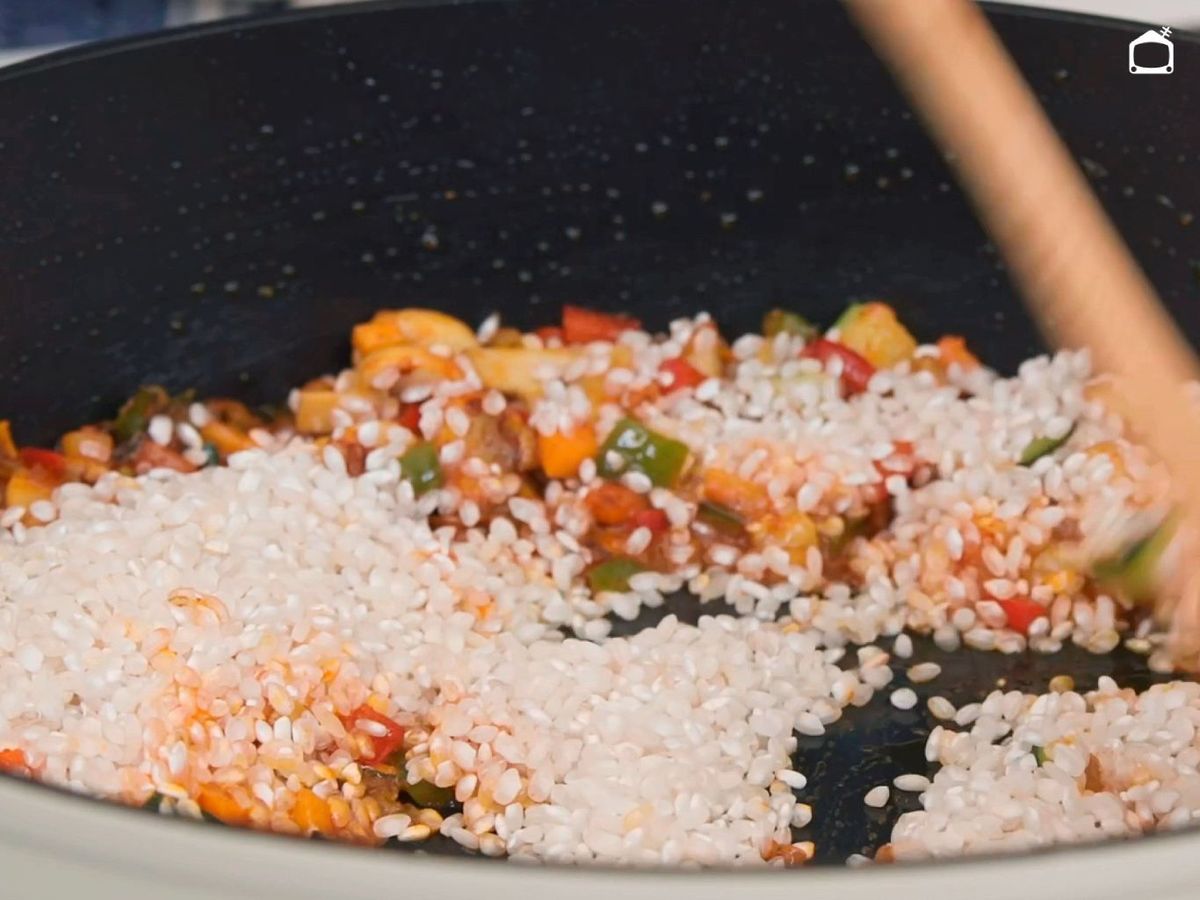 Sofreír los granos de arroz con el sofrito antes de añadir el caldo