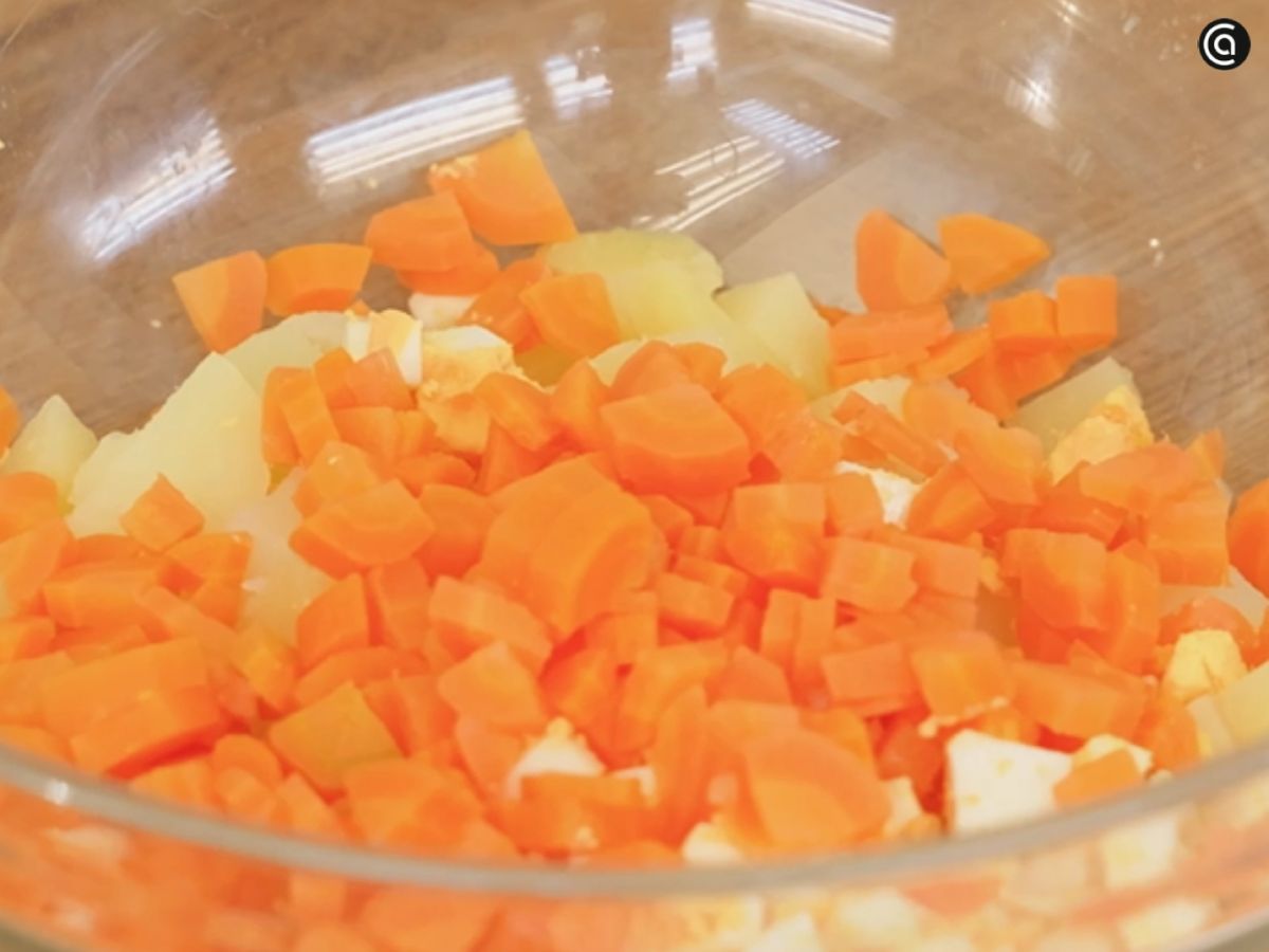 Patata, zanahoria y huevo cocidos y troceados, formando la base de la ensaladilla.