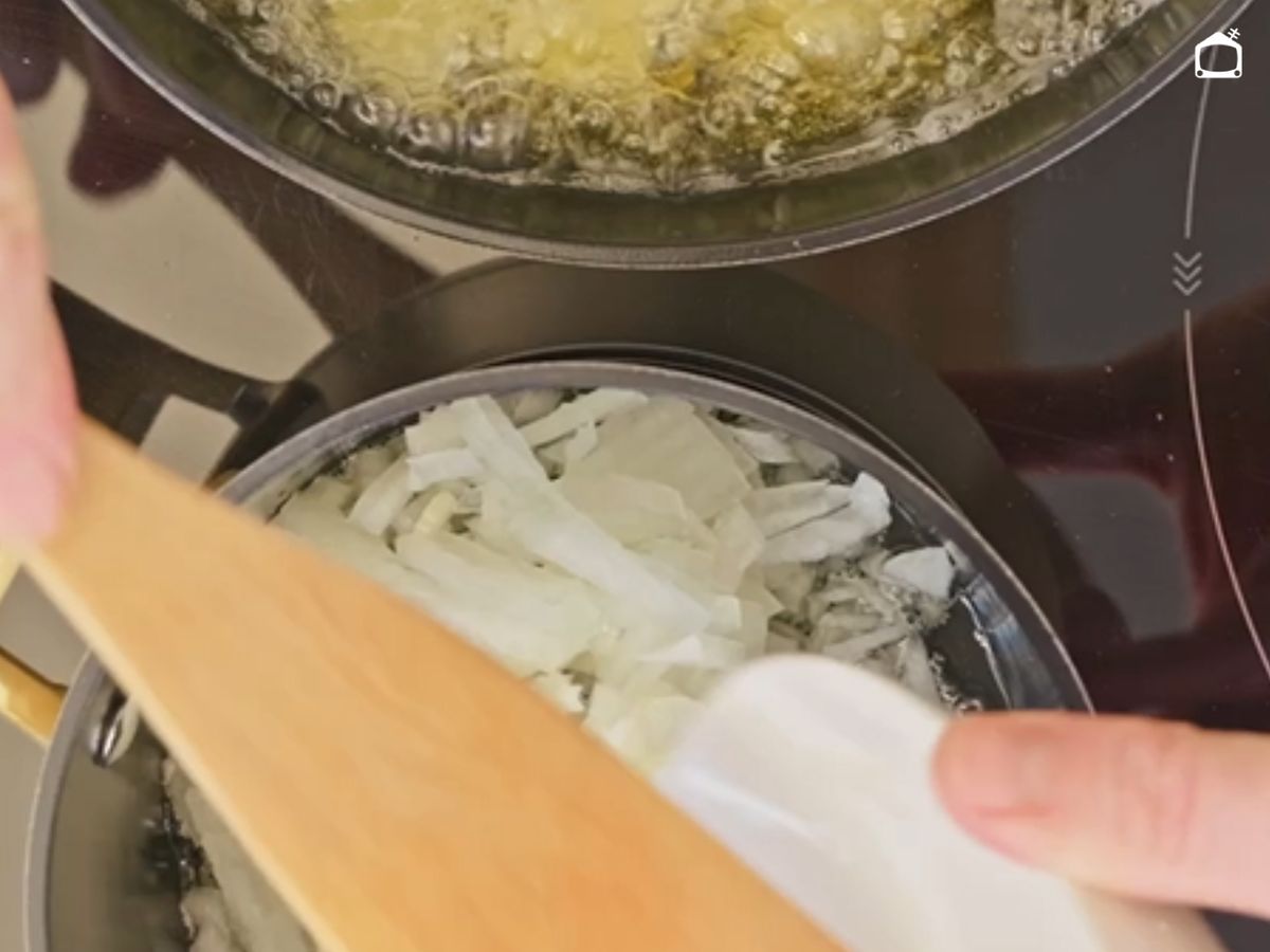 Las patatas se fríen en abundante aceite mientras la cebolla comienza a pocharse a fuego suave.