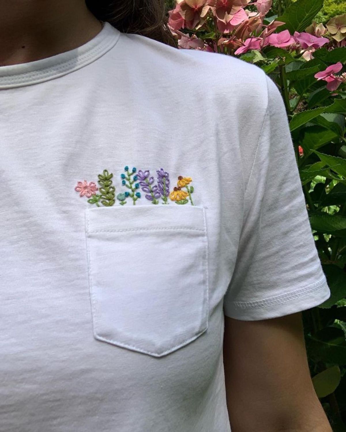 Camiseta con flores bordadas saliendo del bolsillo.