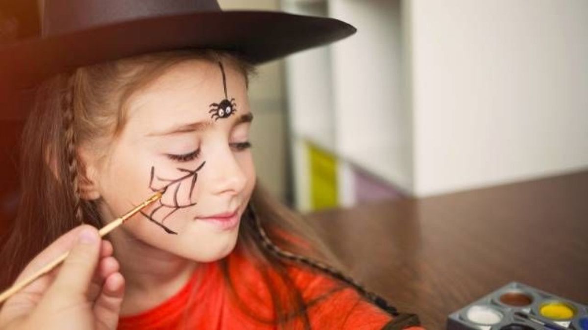 Una simpática araña dibujada en la cara da un toque diferente a un disfraz de bruja