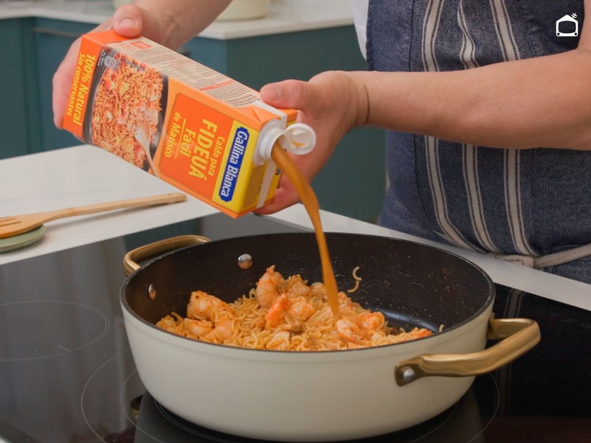 Añade los fideos, vierte el caldo y cocina la fideuá