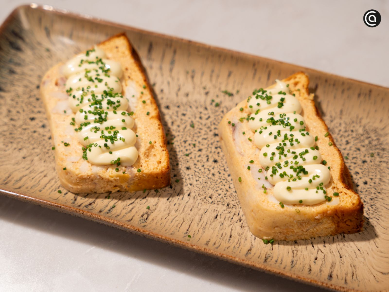 Las rebanadas del pastel se presentan con mayonesa y cebollino, listas para lucir en una mesa festiva.