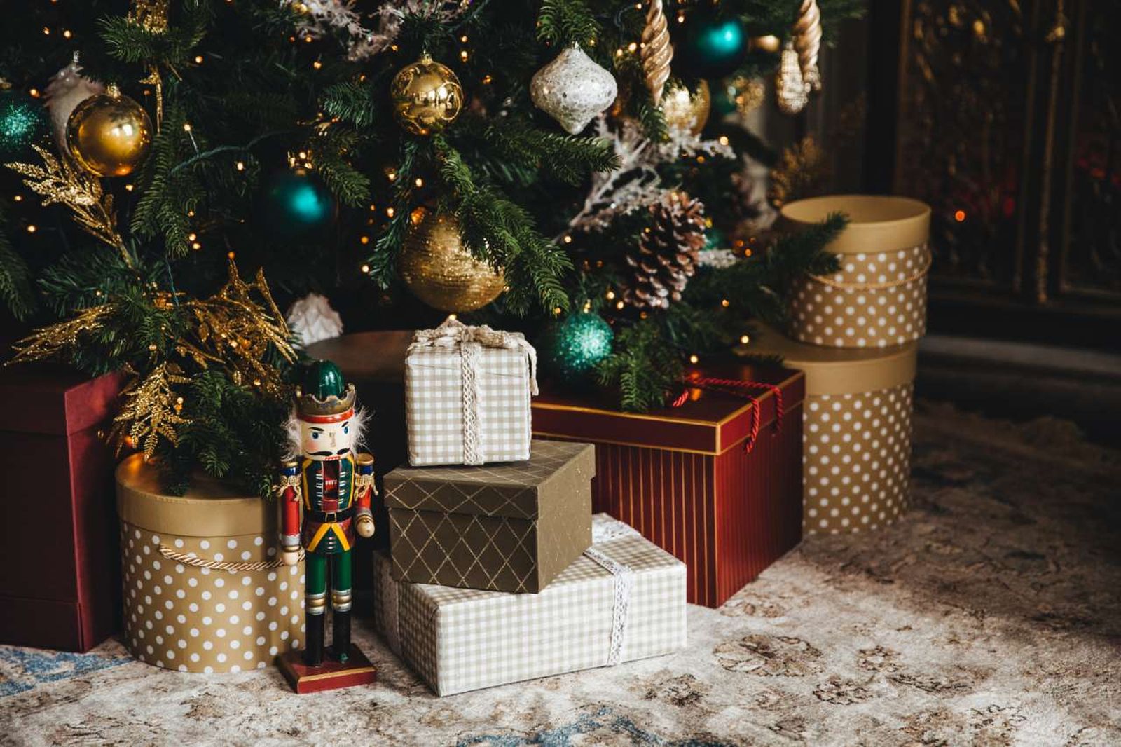 Árbol de Navidad con el pie decorado con regalos y una figura de Cascanueces.