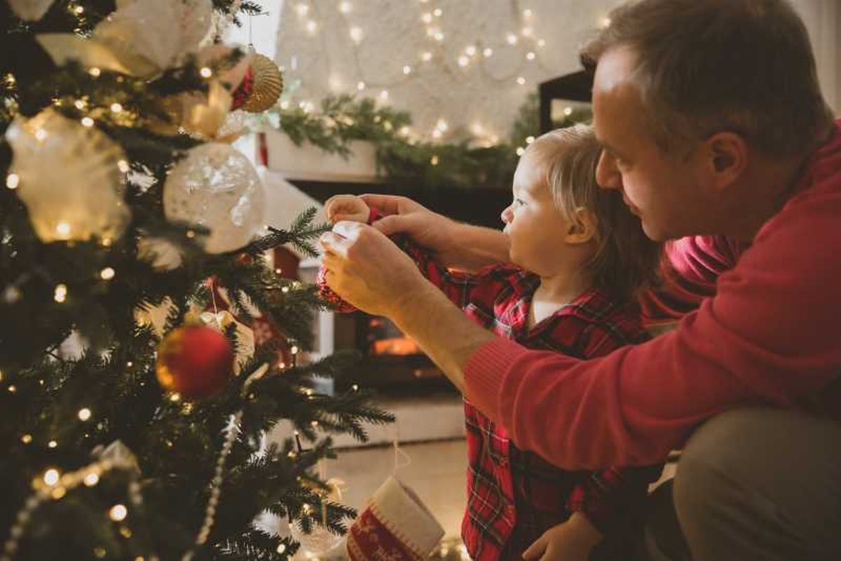 Familia decorando un árbol de Navidad de estilo nórdico.