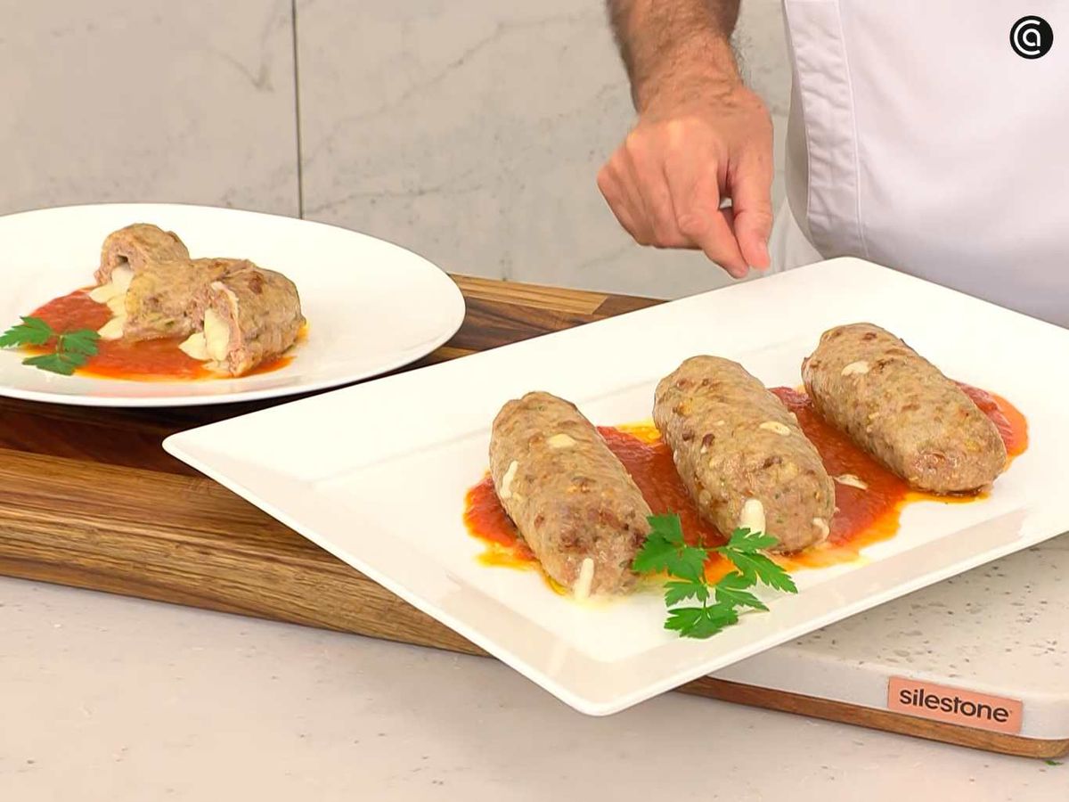 Sirve el rollo de carne picada relleno de queso sobre salsa de tomate