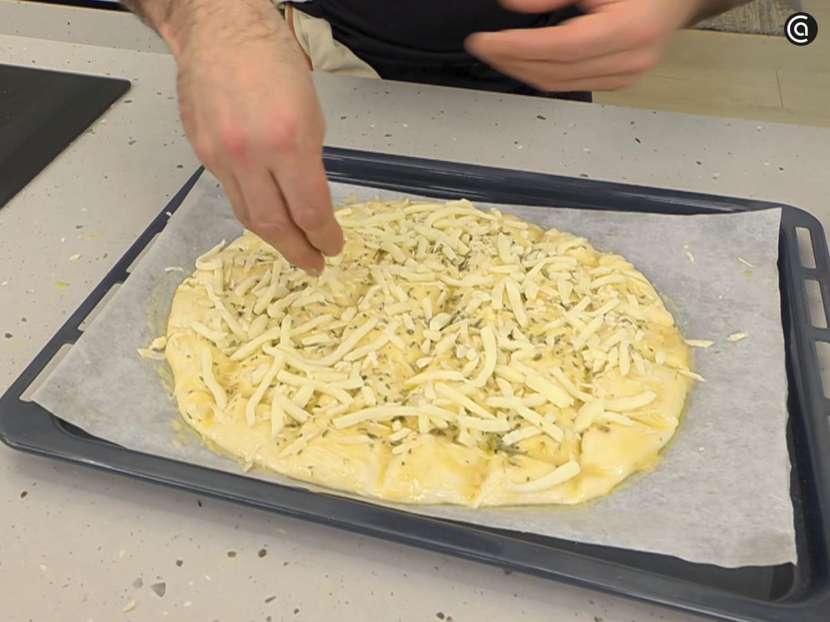 Cubre la masa con crema de ajo, añade los quesos, orégano y hornea