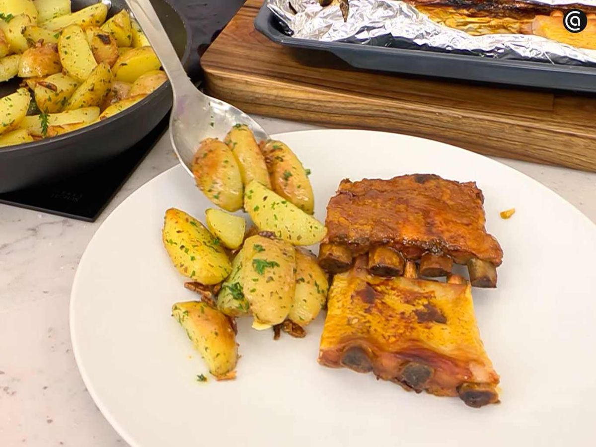Sirve el churrasco de cerdo con patatas al ajo y orégano