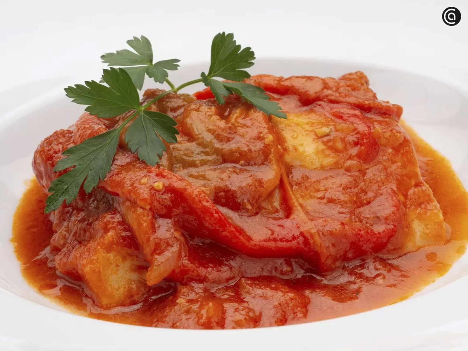 Ración de bacalao a la riojana lista para servir, con su salsa de tomate y pimientos.