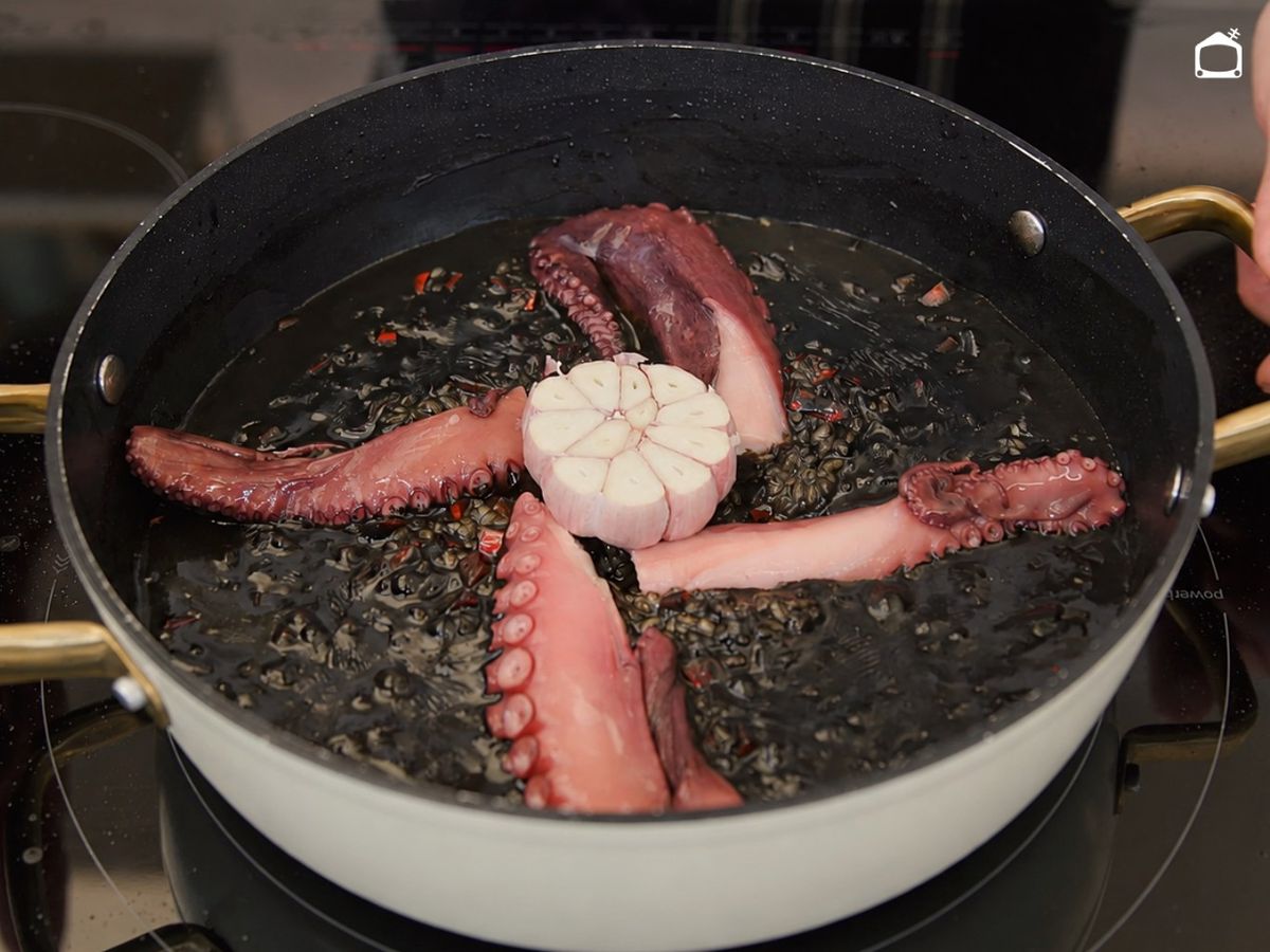 Coloca el pulpo y el ajo sobre el arroz antes de hornear
