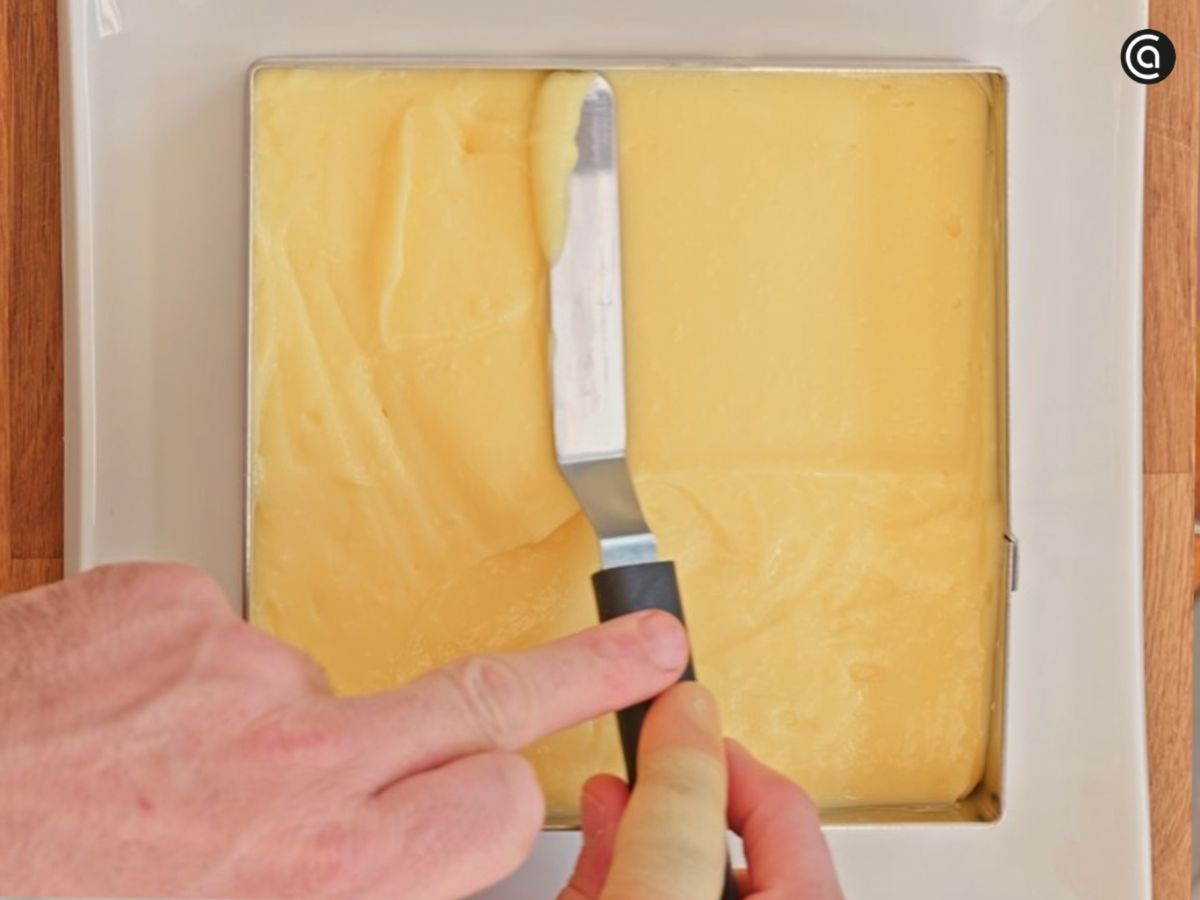 La crema pastelera se reparte sobre la base de galletas formando una capa uniforme.