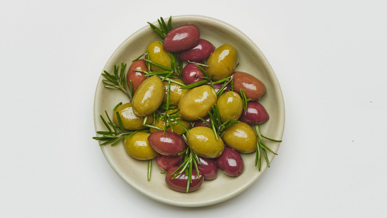 Aceitunas verdes y moradas aliñadas con romero: una muestra de la diversidad cromática y organoléptica de este ingrediente icónico.