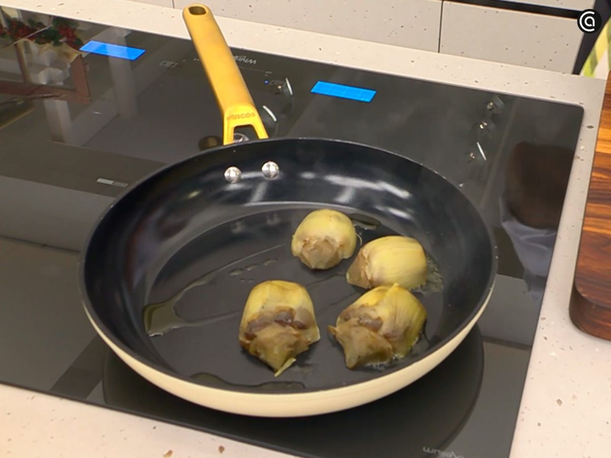 Corta las alcachofas cocidas en mitades y saltéalas en la sartén