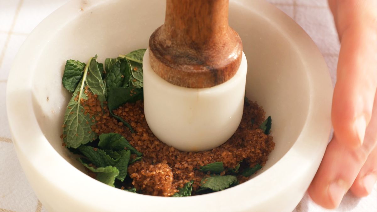 Combina las hojas de menta y el azúcar moreno en el mortero para crear una mezcla aromática