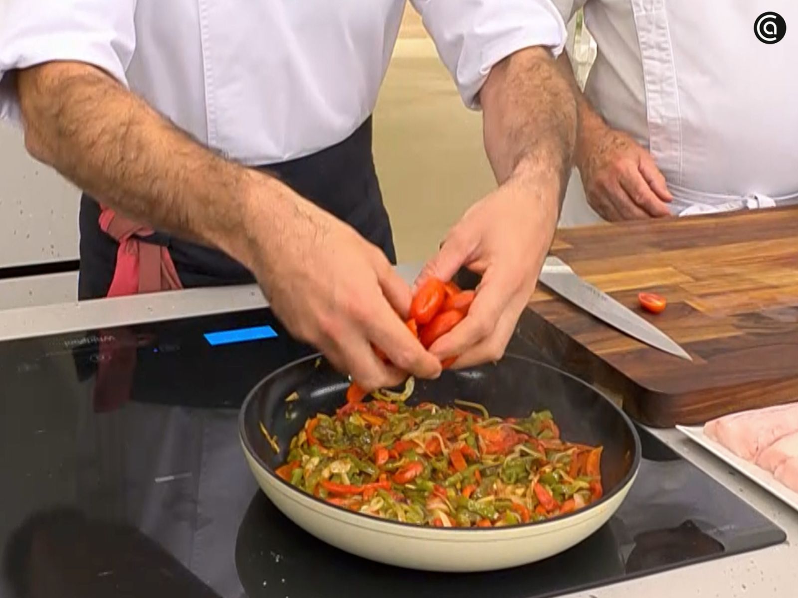 Añade los tomates cherry partidos a la sartén con las verduras.