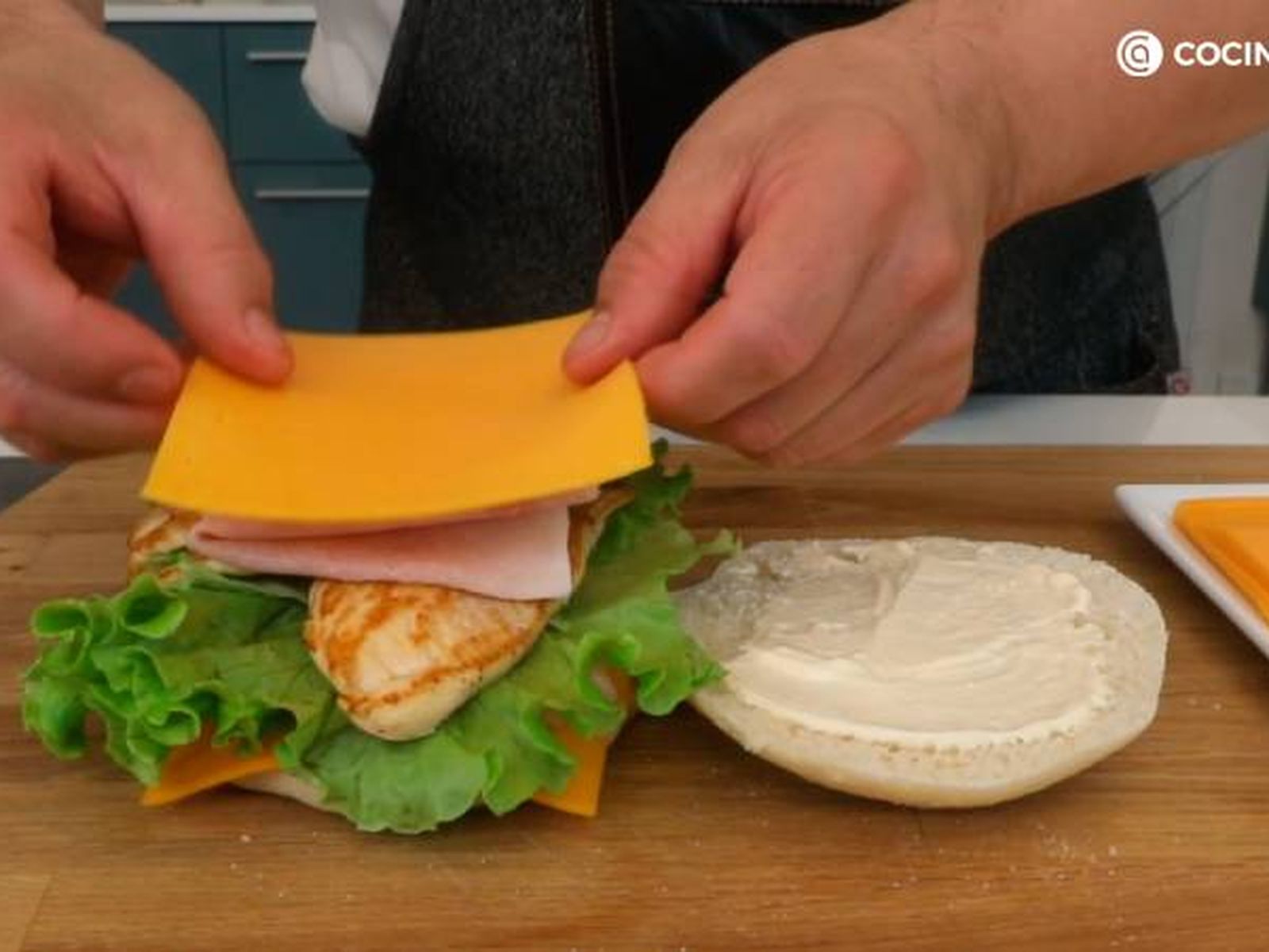 Rellena el bocadillo con tomate, lechuga, pollo, jamón york y queso cheddar