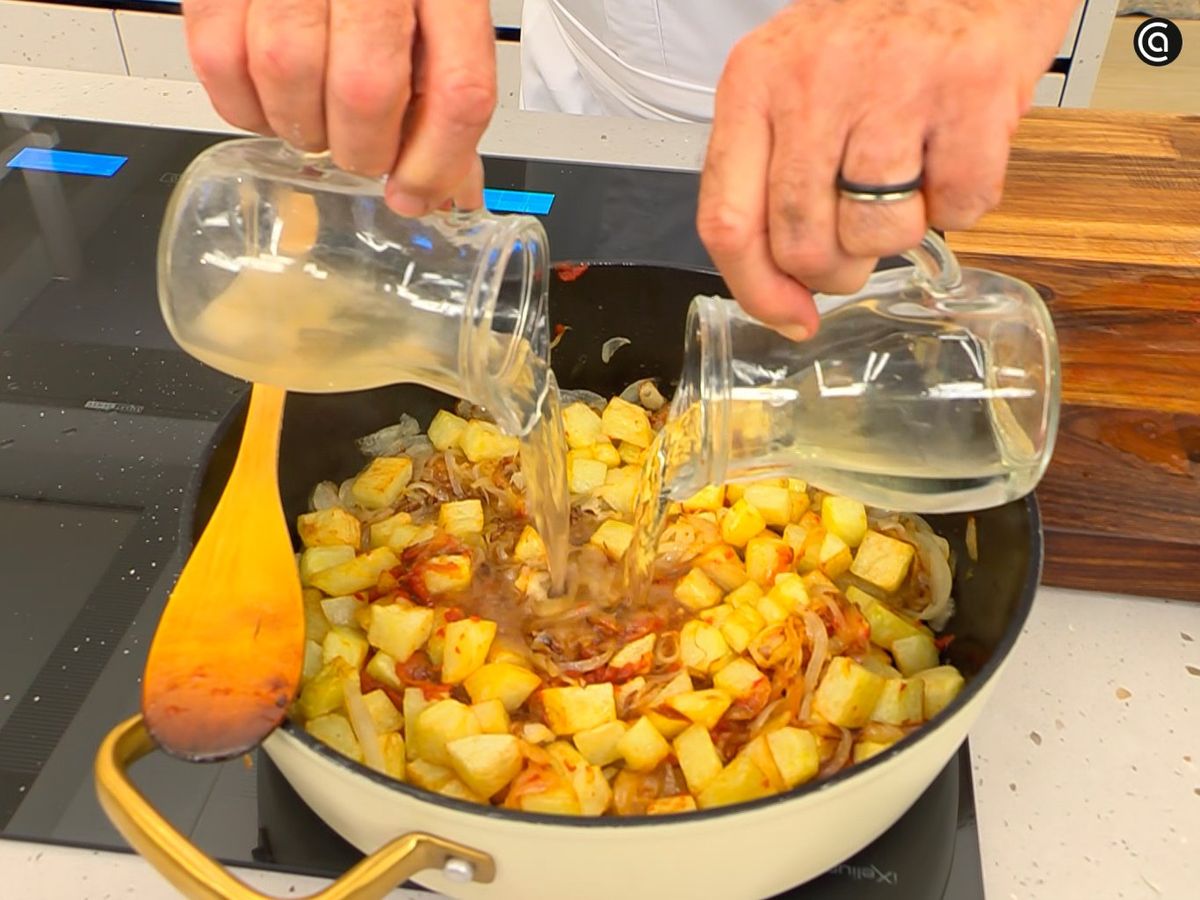 Añade la pulpa del pimiento choricero, las patatas y el vino blanco a la cazuela con la cebolla