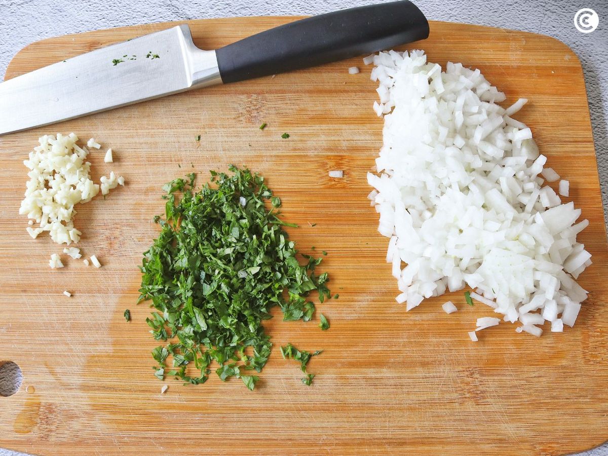 Picar cebolla, ajo y perejil para hacer rape en salsa verde
