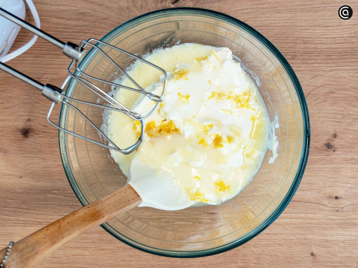 Mezcla el queso crema con la leche condensada; luego añade el zumo de limón y la ralladura