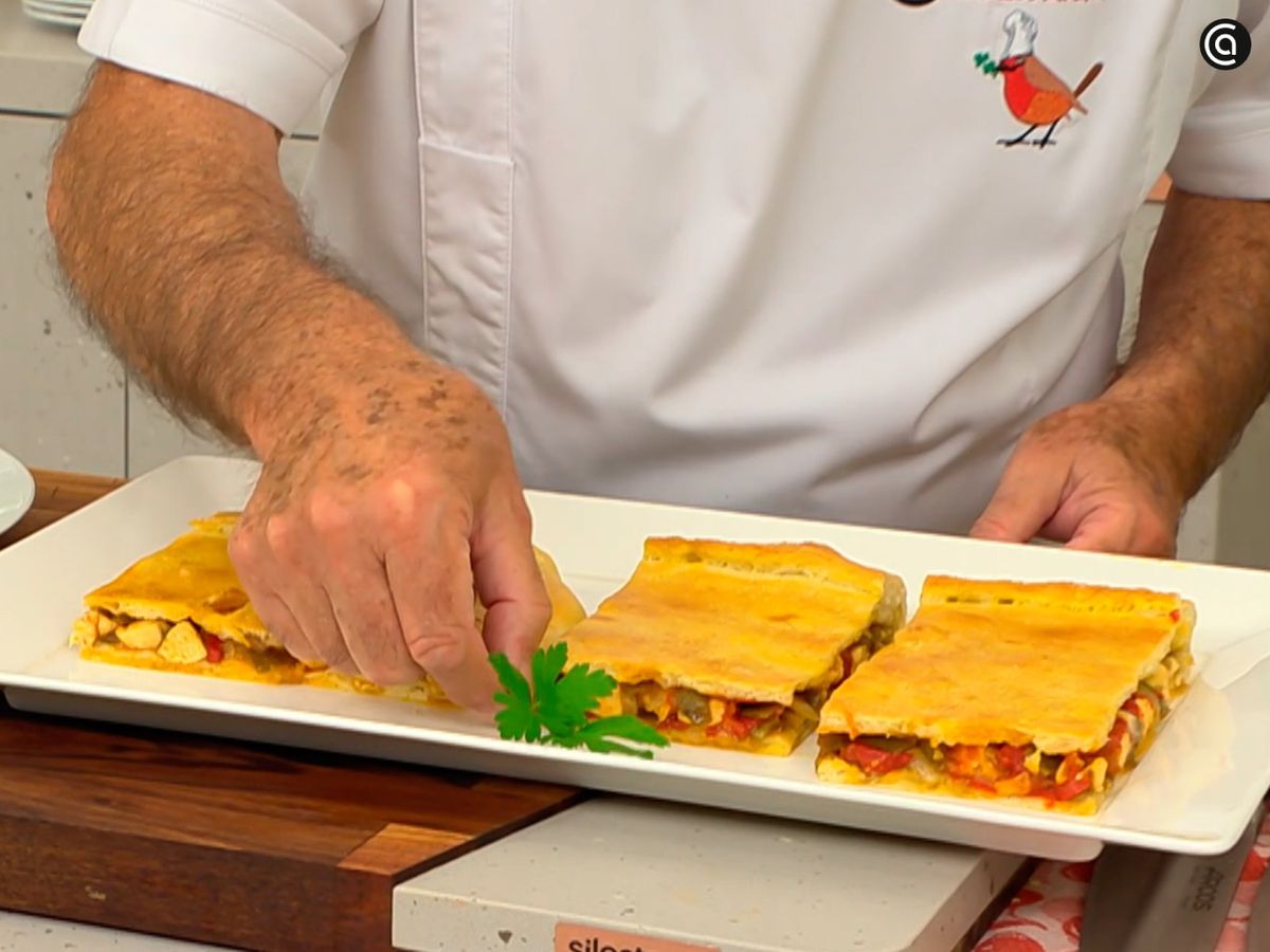 Corta la empanada gallega de pollo en porciones y decora con hojas de perejil