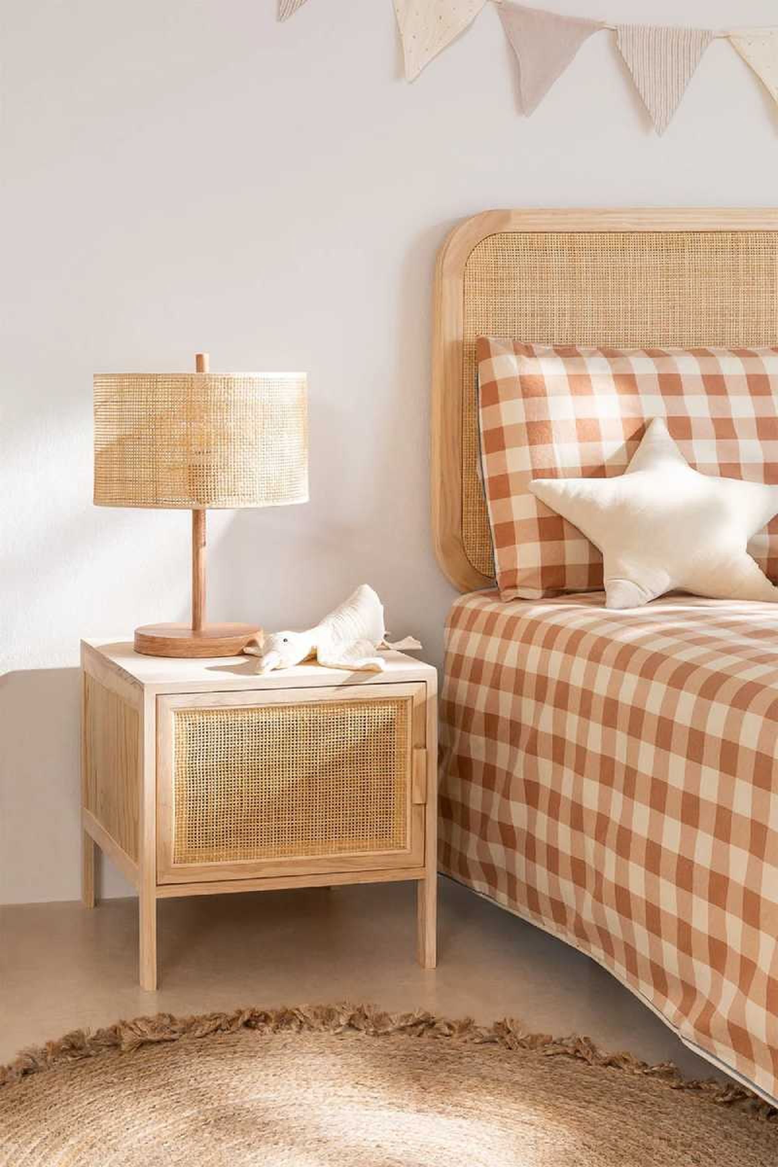 Dormitorio infantil con complementos de ratán y cojín de estrella.