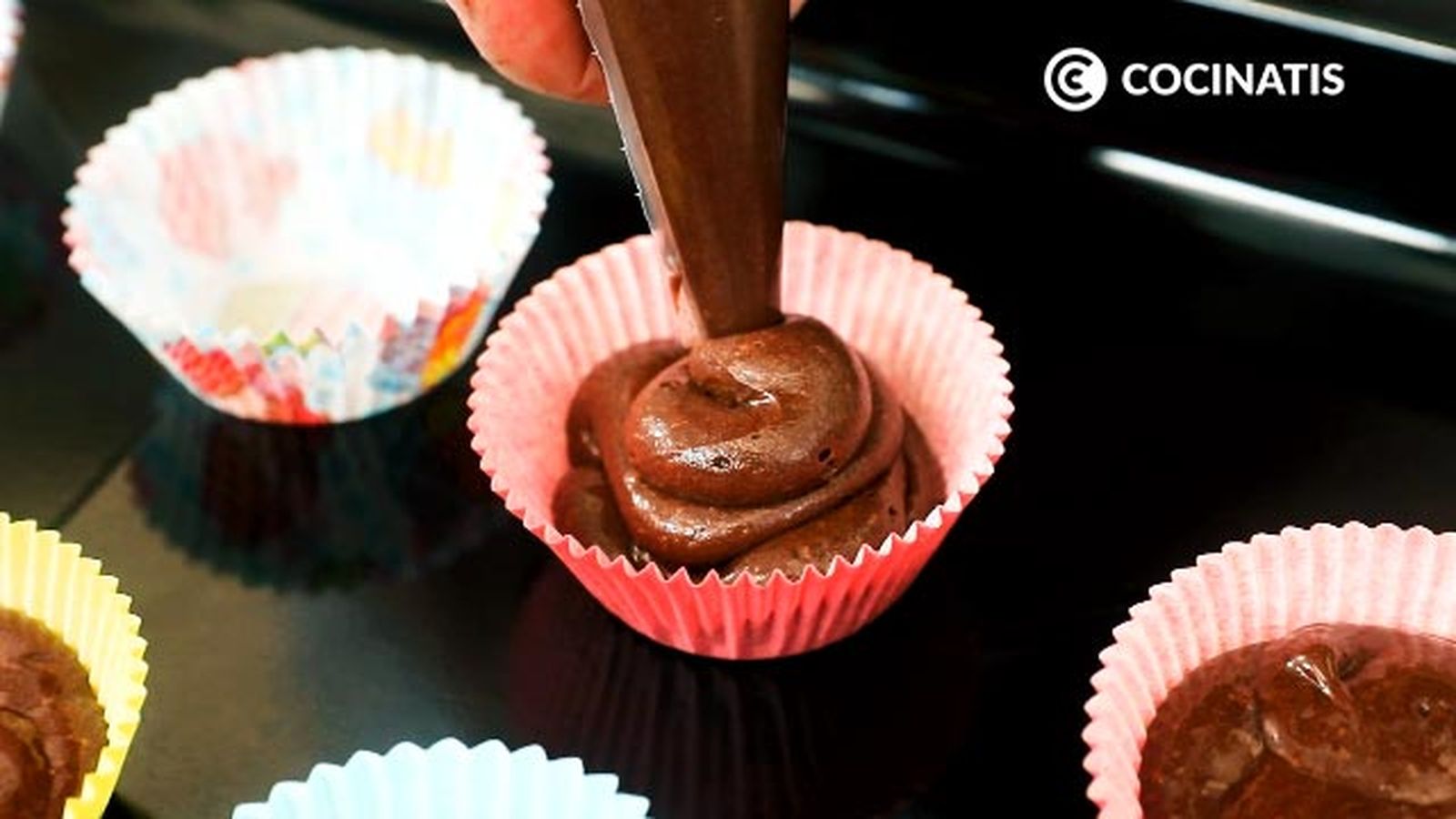 Rellena los moldes con una manga pastelera Receta de magdalenas de chocolate y avellanas paso 5