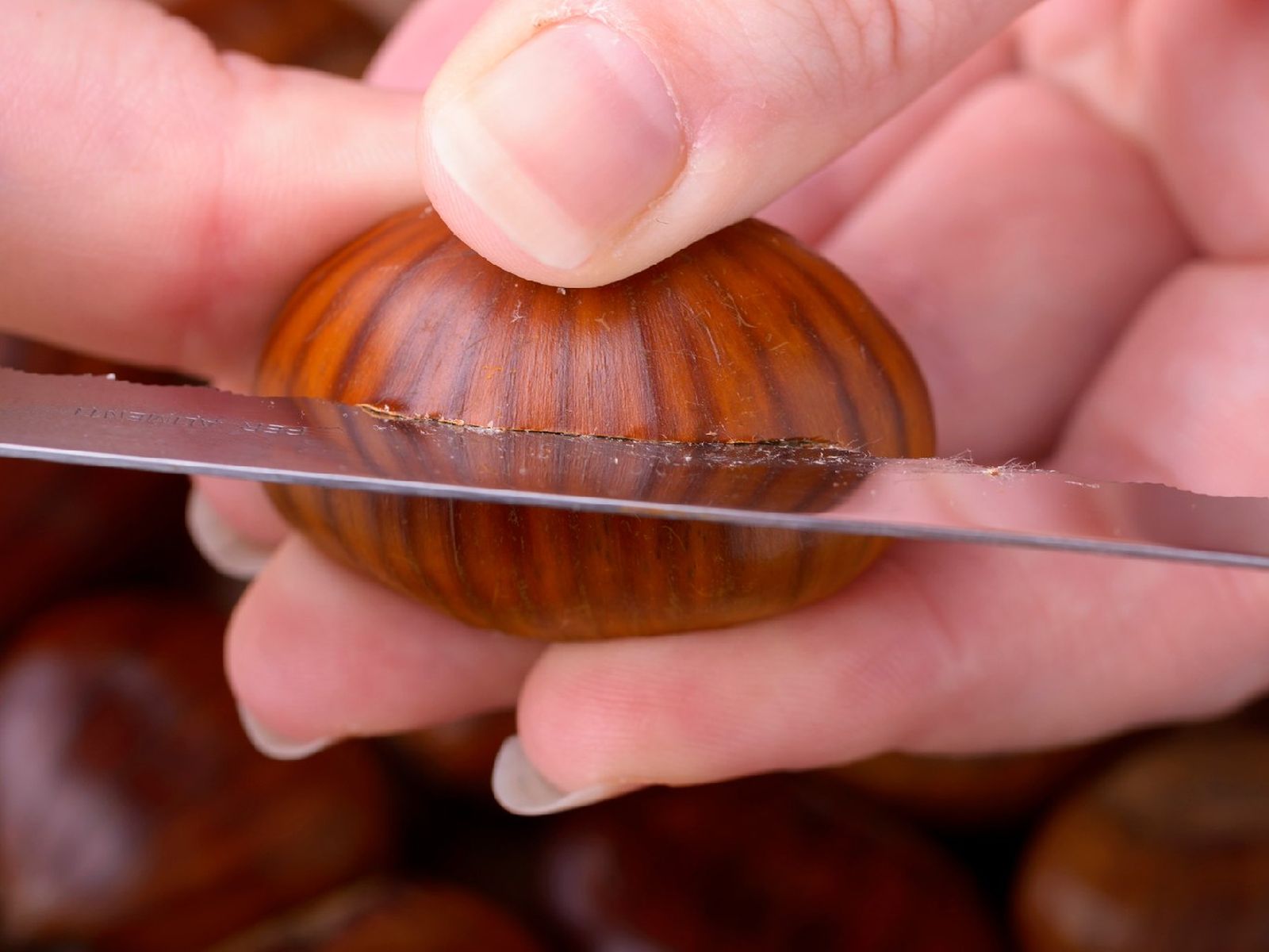 Con un cuchillo, haz un corte en cruz a cada castaña