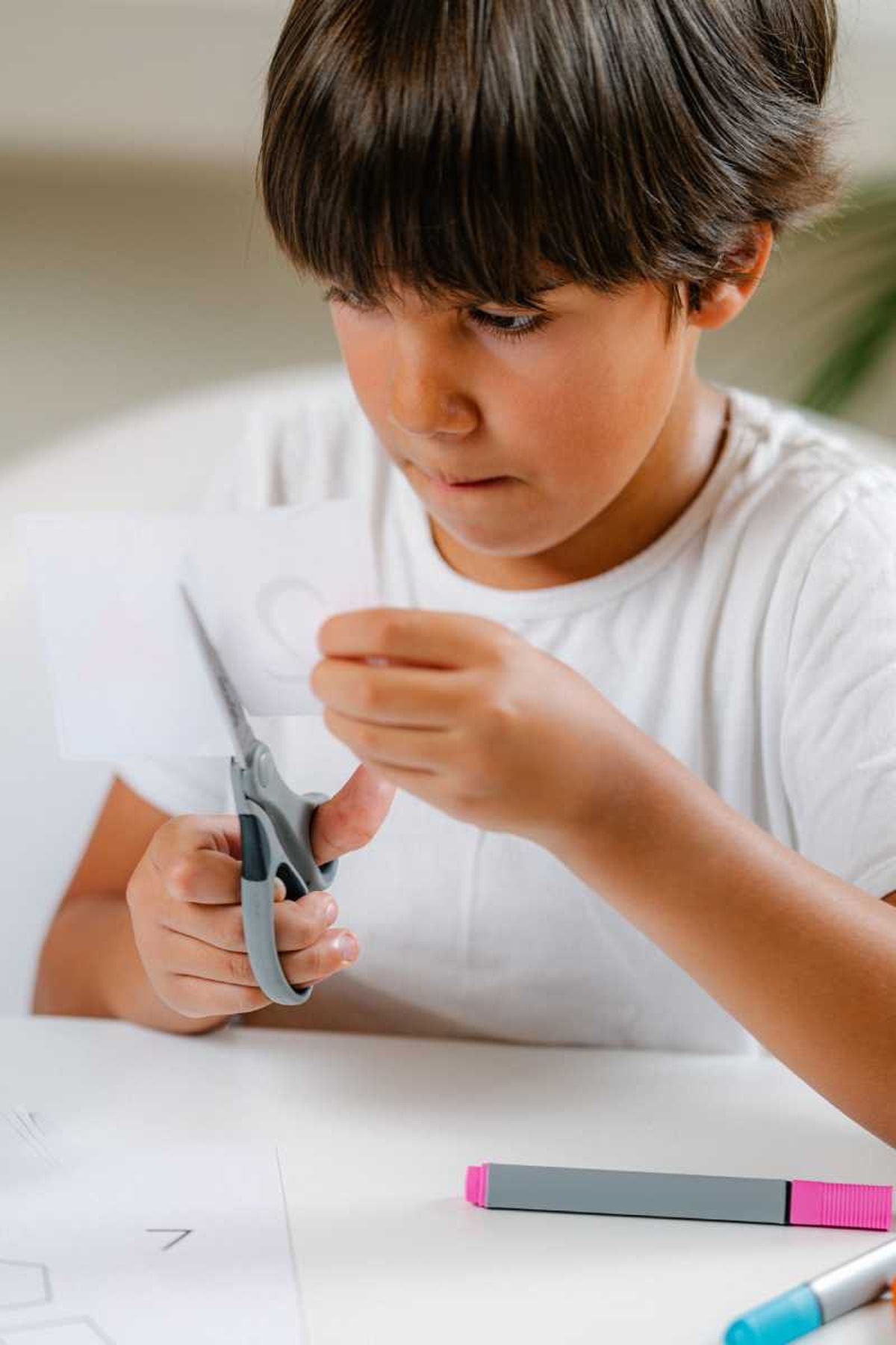 Un niño cortando papel para elaborar una manualidad.