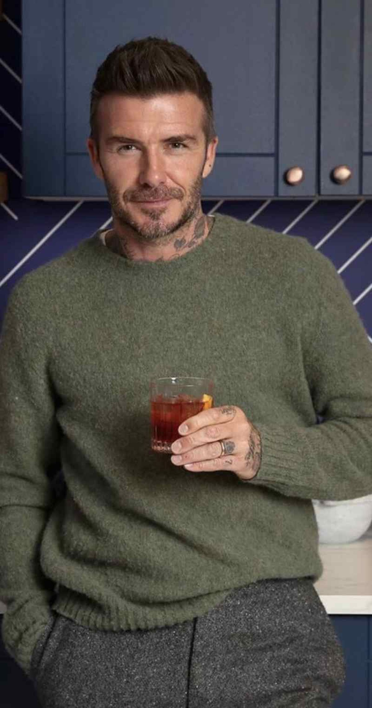 David Beckham con pantalón gris y jersey verde oliva