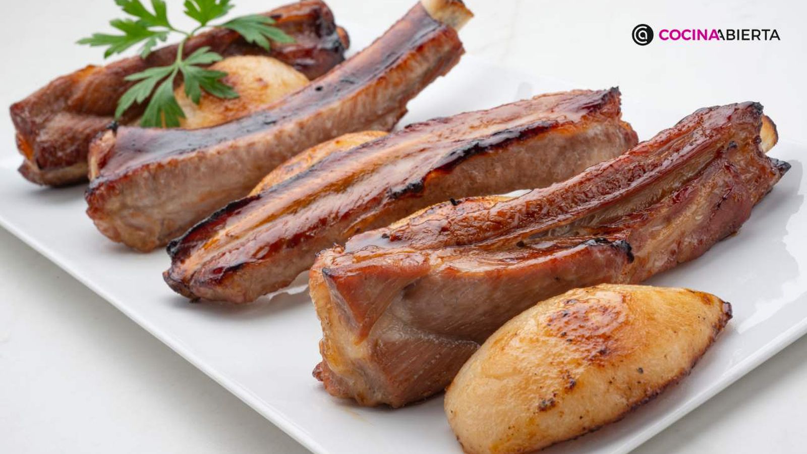Jugosas costillas de cerdo asadas, acompañadas de peras, como guarnición