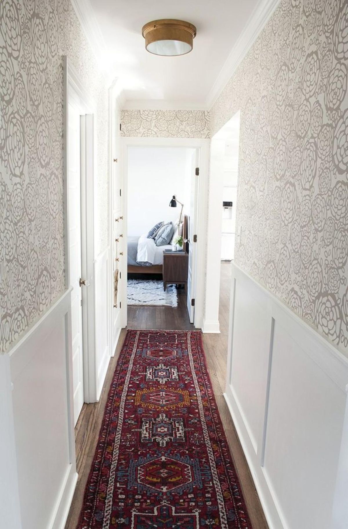 Pasillo largo y estrecho con papel pintado y alfombra.