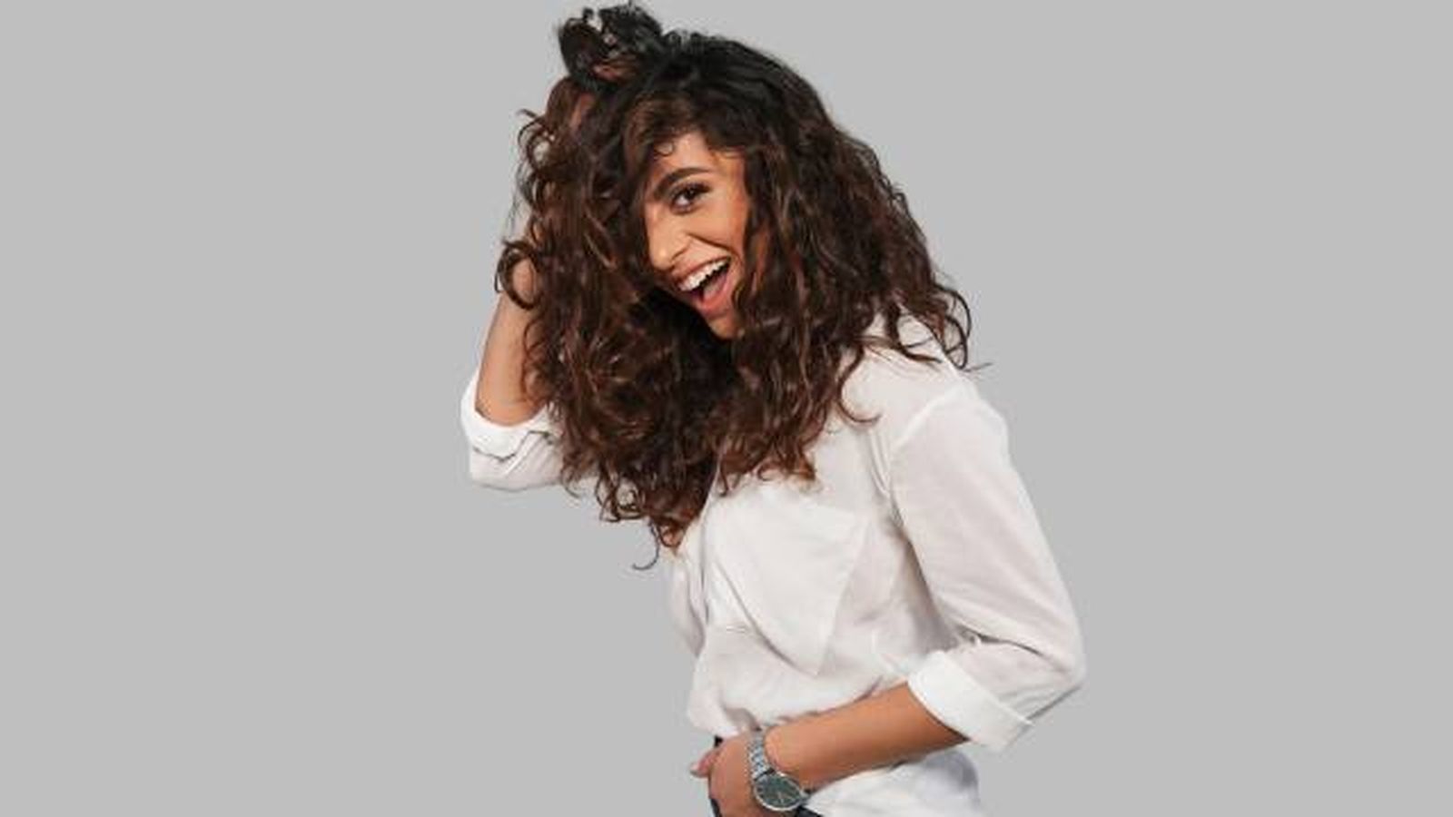 mujer sonrie mientras se lleva la mano al cabello color chocolate mujer sonrie mientras se lleva la mano al cabello color chocolate
